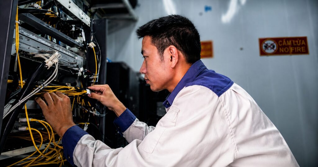 Đỗ Quang Thủy kiểm tra hệ thống cáp tại phòng thiết bị trong quá trình vận hành các trạm viễn thông vùng núi Chí Linh, Hải Dương.