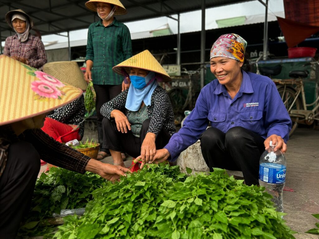 Bà Dương Thị Bé cùng các tiểu thương trao đổi rau tại chợ, công việc gắn bó nhiều năm của người phụ nữ vượt khó Hải Dương.