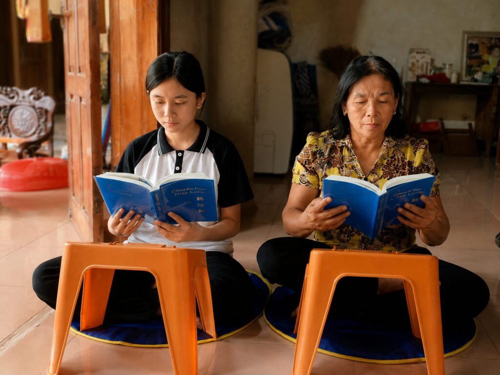 Bà Dung cùng con cháu đọc sách trong nhà, ghi lại khoảnh khắc sinh hoạt thường ngày gắn với hành trình Pháp Luân Công thay đổi cuộc sống.