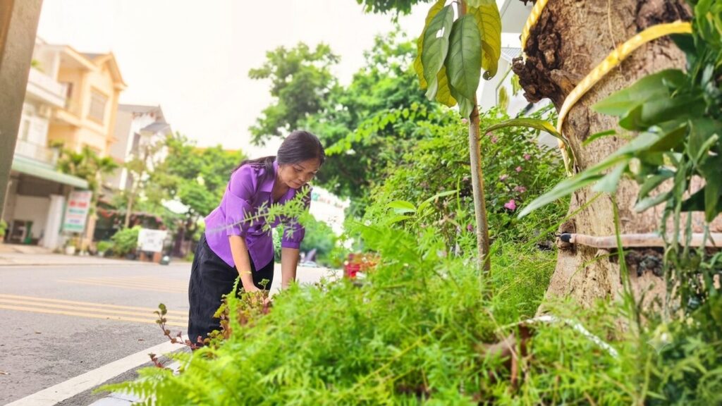 Nguyễn Thị Minh chăm sóc cây xanh trước nhà tại Vĩnh Yên, hình ảnh phản ánh nhịp sống bình dị của nhân vật sau nhiều năm làm nghề hộ sinh.