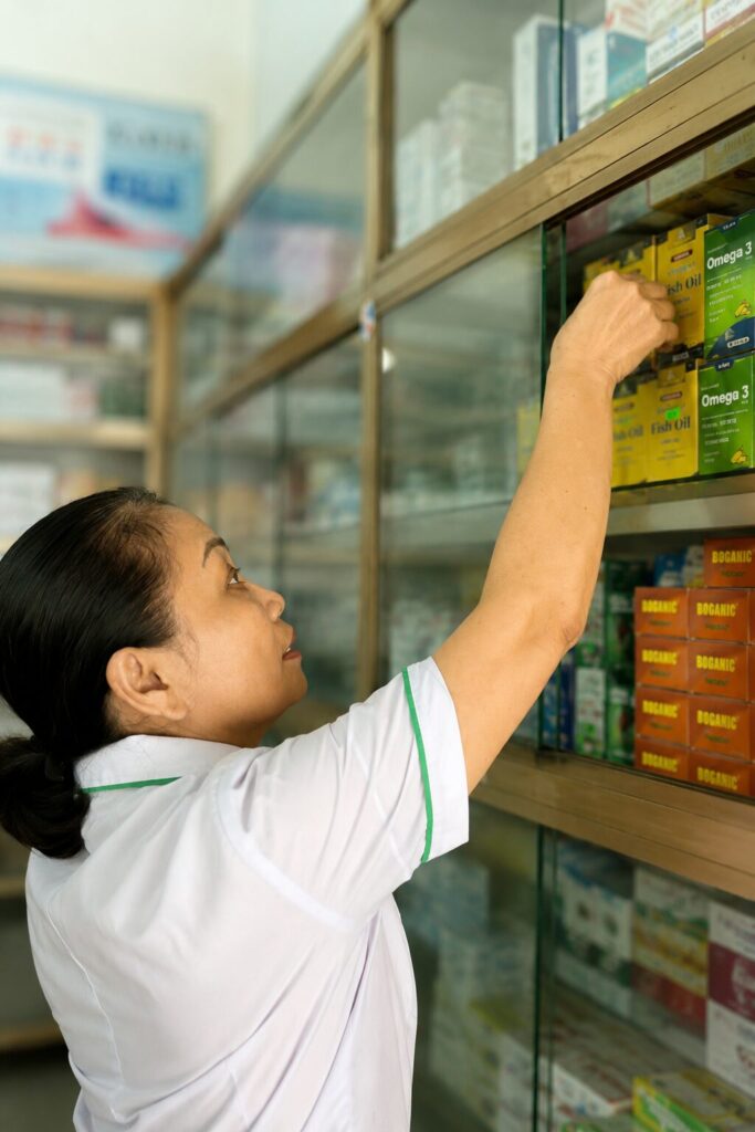 Bà Trần Thị Tâm kiểm tra và lấy thuốc trên kệ tại Nhà thuốc Hảo Tâm, nơi bà đã gắn bó nhiều năm với nghề dược.