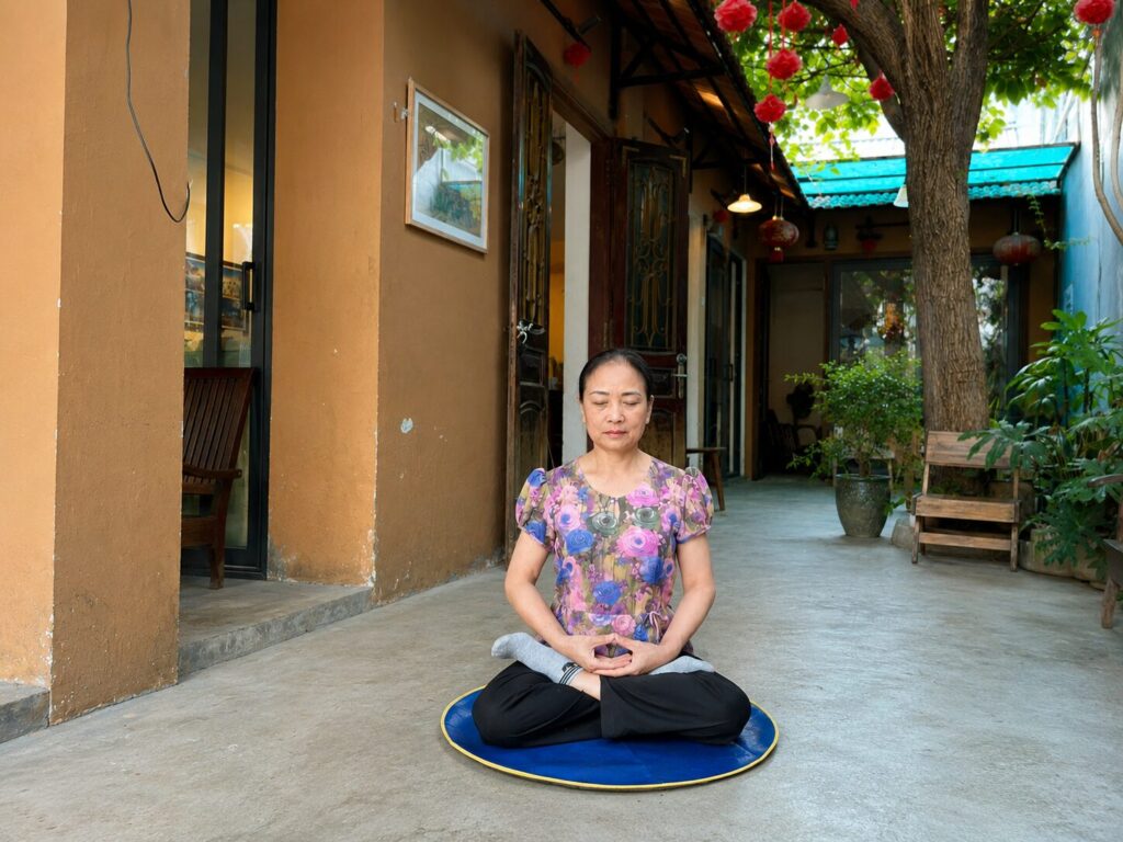 Bà Trần Thị Tâm ngồi luyện công trong sân nhà vào buổi sáng, duy trì thói quen rèn luyện sức khỏe sau giờ làm việc.