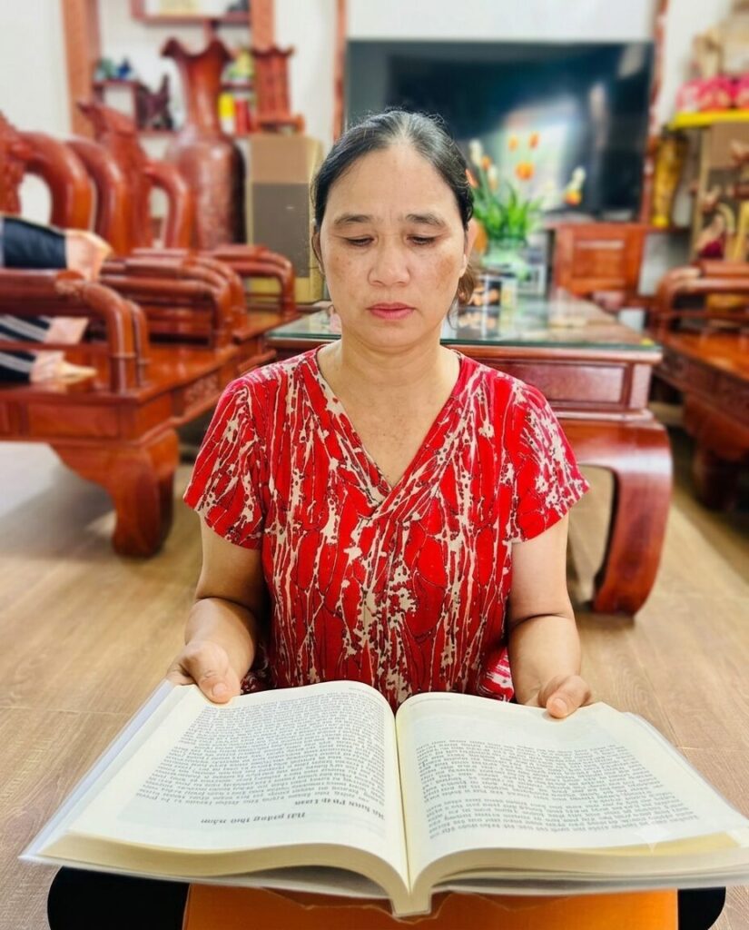 Bà Nguyễn Thị Mùi đọc sách tại nhà, hình ảnh minh họa quá trình thay đổi nhận thức trong hành trình buông bỏ hận thù và vượt qua những năm tháng khó khăn.