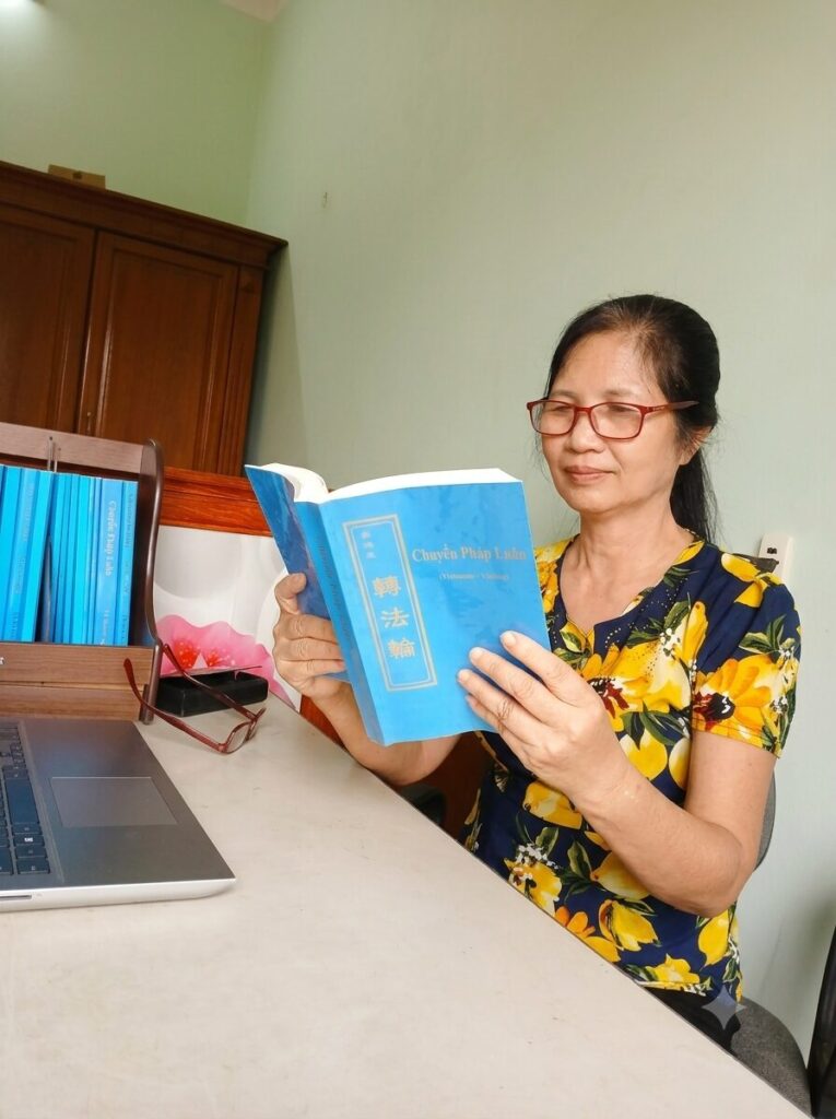Cô giáo Bùi Thị Hà đọc sách tại nhà bên chiếc máy tính cá nhân, ghi lại một khoảnh khắc trong hành trình cô giáo vượt qua bệnh tật hiểm nghèo.