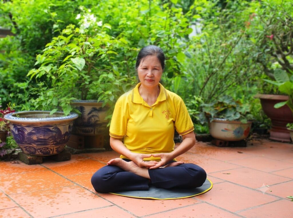Cô giáo Bùi Thị Hà ngồi thiền trong khuôn viên nhà, minh họa sinh hoạt thường ngày sau hành trình cô giáo vượt qua bệnh tật hiểm nghèo.