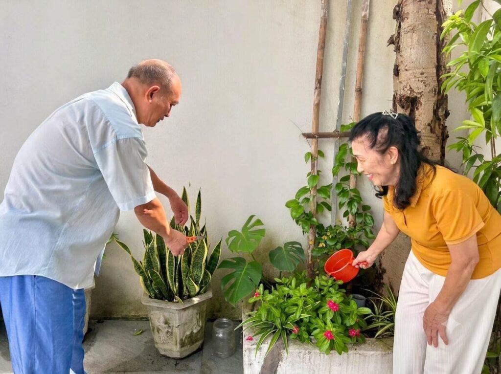 Vợ chồng cô giáo Trần Thị Yên chăm sóc cây trong khuôn viên nhà ở bài viết Cuộc đời thứ hai cô giáo Trần Thị Yên, ghi lại hoạt động thường nhật.
